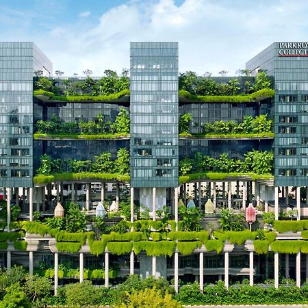 Parkroyal Collection Pickering, Сингапур Екстериор снимка The photo shows a modern multi-story building characterized by a sleek, glass facade. The structure features multiple floors with abundant greenery, including vertical gardens and terraces filled with plants, creating a striking contrast between the 