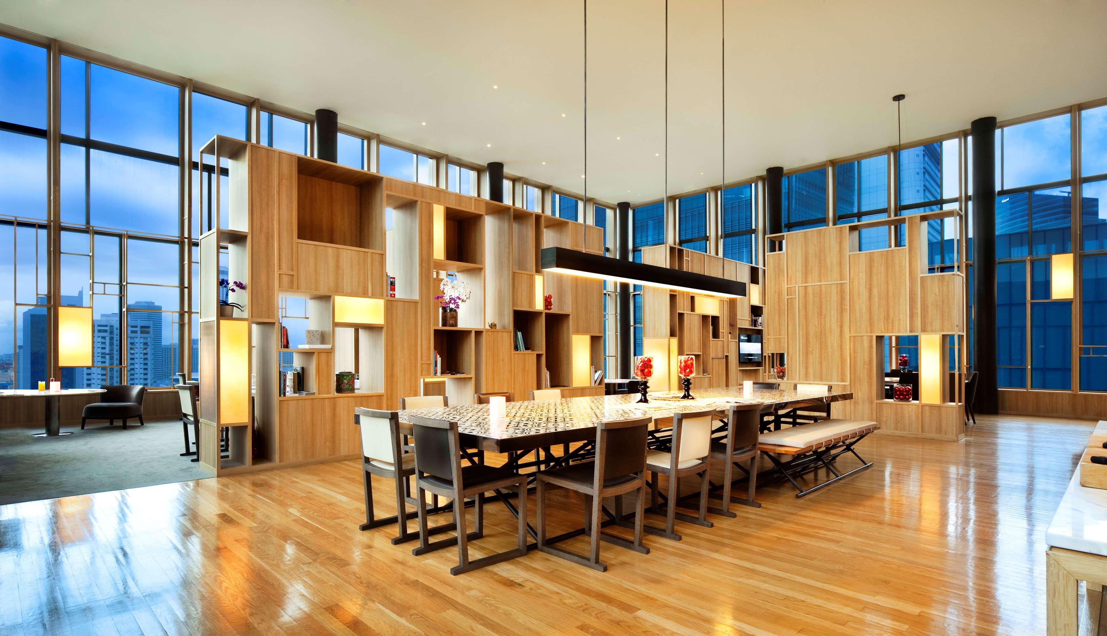 Parkroyal Collection Pickering, Сингапур Екстериор снимка The image shows a modern dining area or common space with an open layout. The room features large windows that allow natural light to flood in, enhancing the warm wooden tones of the décor. 

In the center, there is a long rectangular dining table su