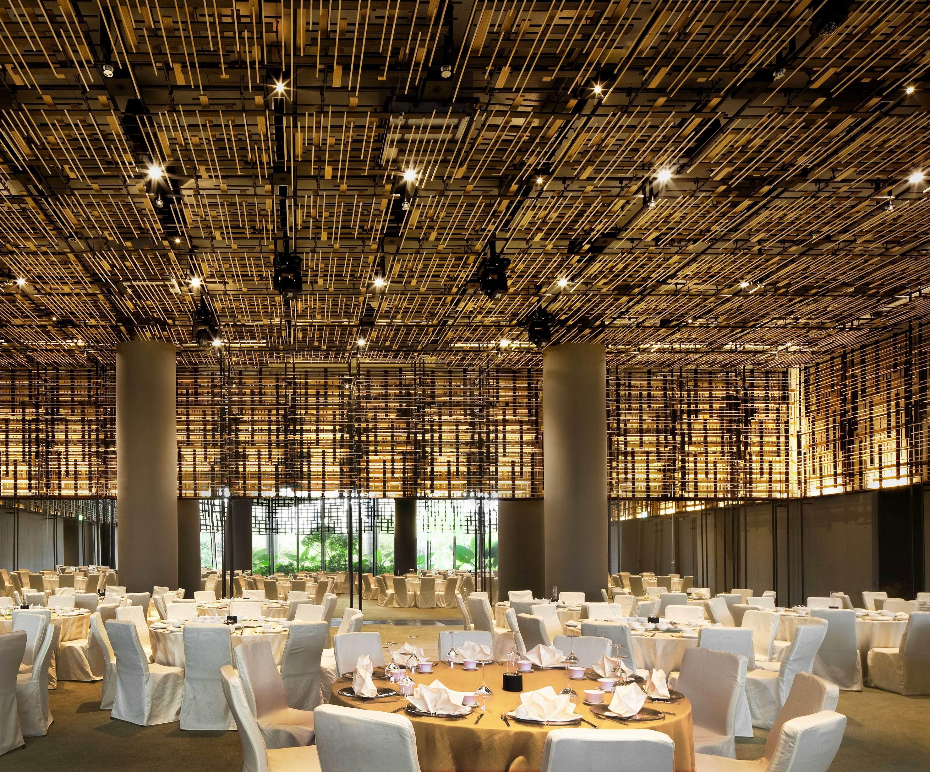 Parkroyal Collection Pickering, Сингапур Екстериор снимка The photo shows a spacious dining area with a modern and elegant design. The ceiling features a unique installation of bamboo or wooden elements that creates a textured appearance. The room is filled with round tables, each set with white tablecloths
