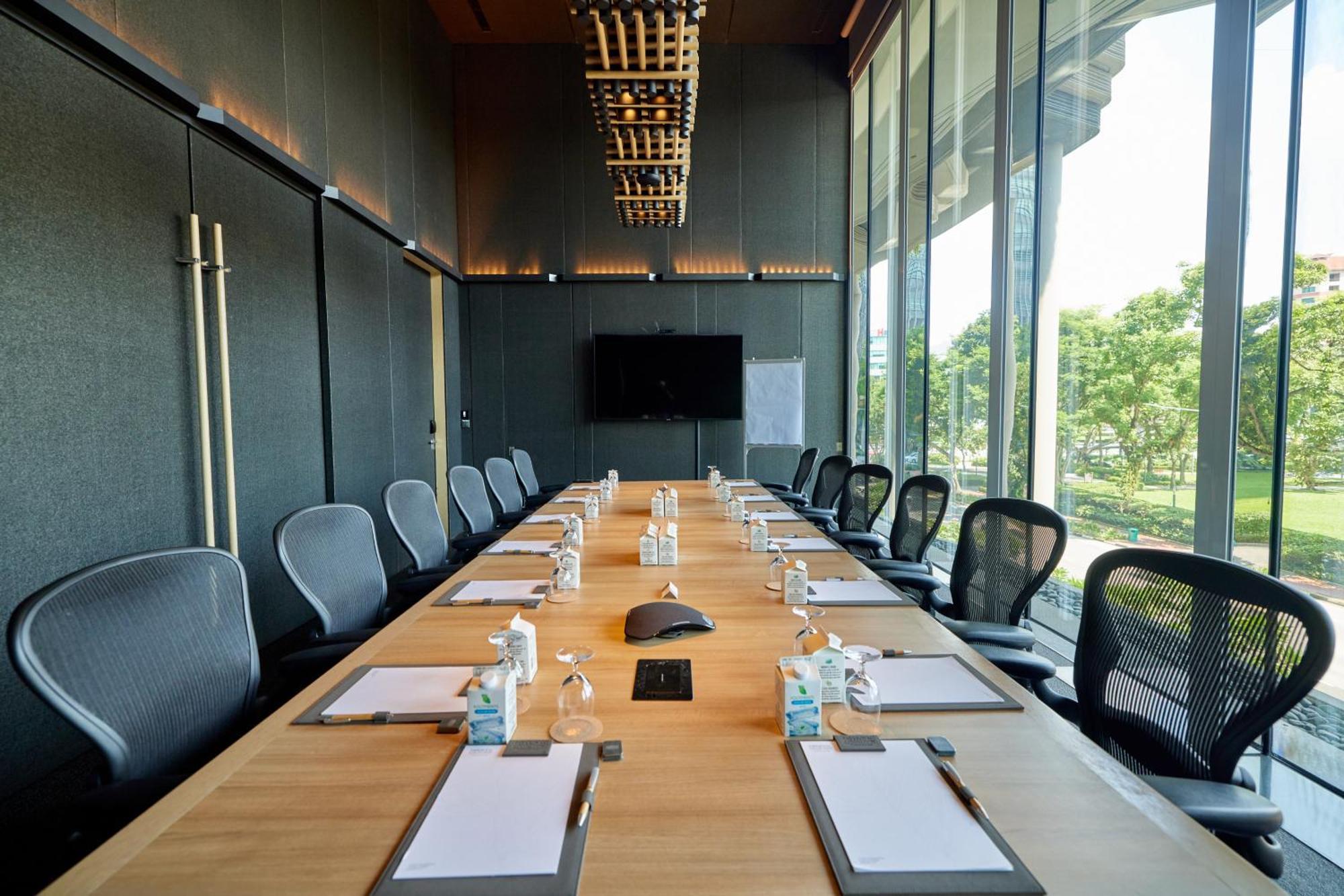 Parkroyal Collection Pickering, Сингапур Екстериор снимка The photo shows a modern conference room designed for meetings. It features a long wooden table surrounded by ergonomic chairs. On the table, there are several pieces of stationery, including notepads and pens, as well as small water bottles. A centr
