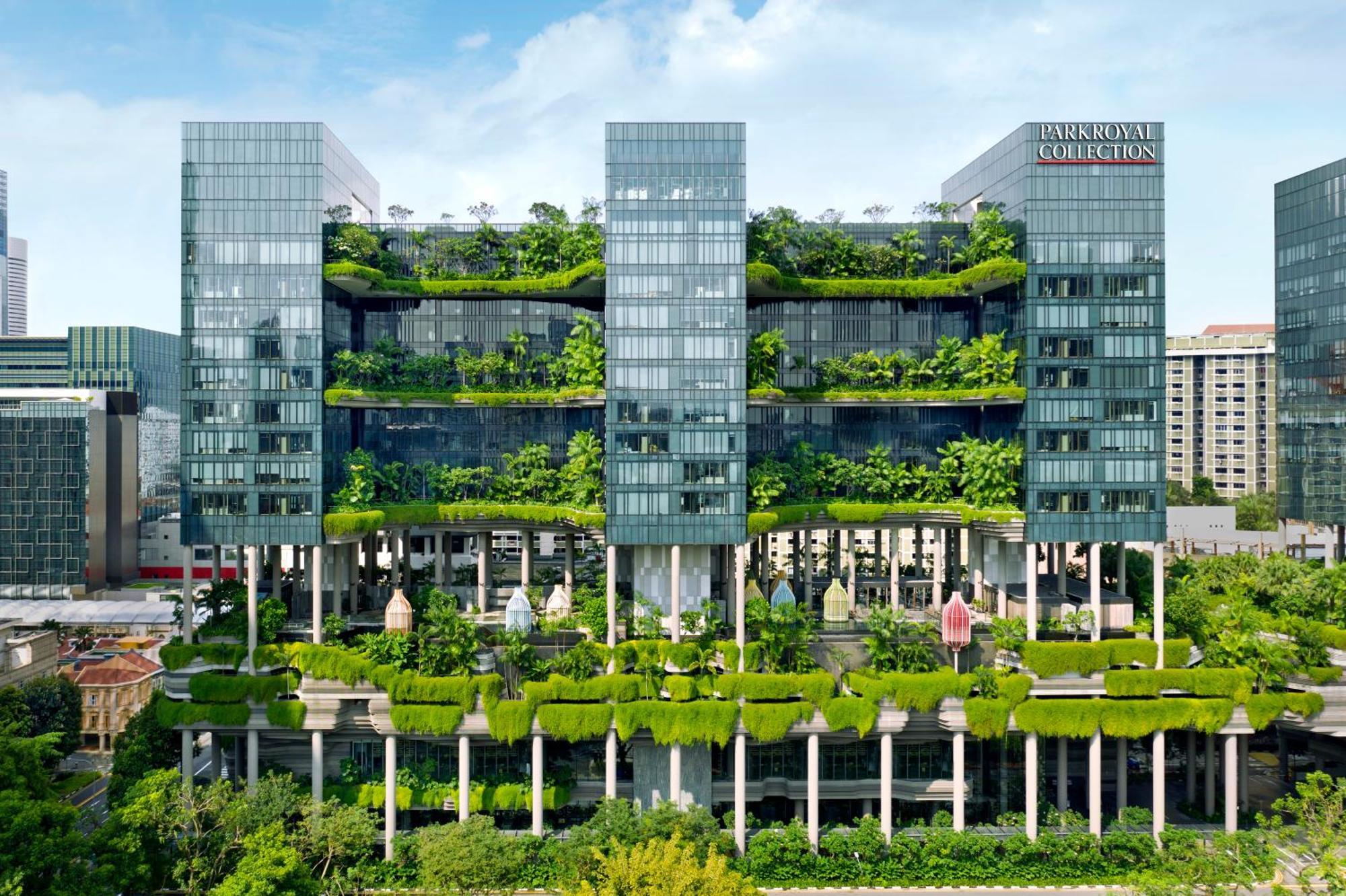 Parkroyal Collection Pickering, Сингапур Екстериор снимка The photo shows a modern multi-story building characterized by a sleek, glass facade. The structure features multiple floors with abundant greenery, including vertical gardens and terraces filled with plants, creating a striking contrast between the 